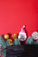 Flat lay medical stethoscope in santa hat and christmas decorations with medical mask on red background