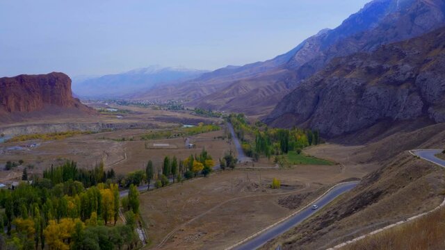 A road in the middle of mountains with trees along