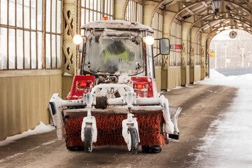 Tractor with rear brush for cleaning sidewalks and walkways.