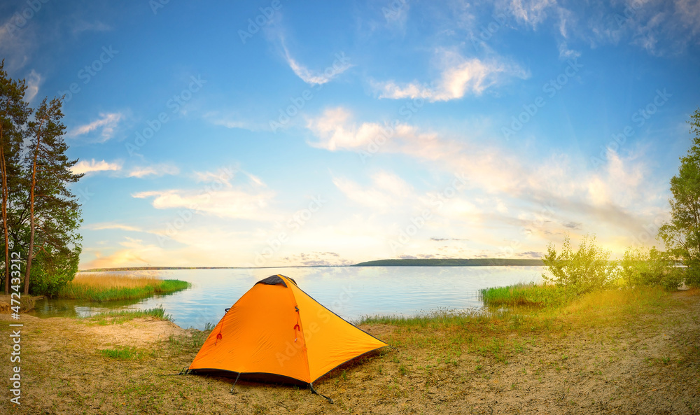 Wall mural orange tourist tent on river bank on sunny day