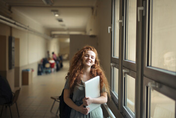 portrait of young girl in a corridor of a school with a computer in hand