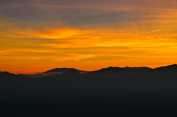 Obraz premium Atmospheric golden twilight sky beautiful morning as the sun rises. The atmosphere was calm, with clouds and mist above the mountains in the morning of winter. 
