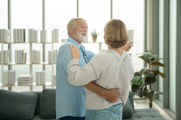 Happy Caucasian senior couple dancing at home