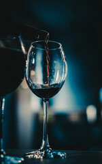 waiter pouring red wine into a glass in cafe or bar