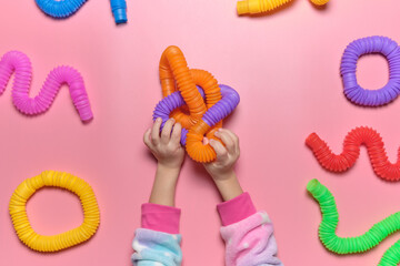 Cheerful little girl in unicorn pajamas plays in a popular toy poptube. An exciting children's game with multi-colored plastic pipes.