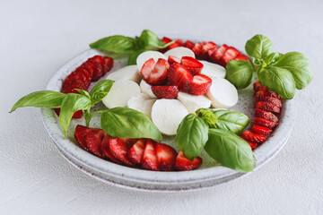 Summer Caprese salad with strawberries. Strawberry salad with basil and mozzarella. Healthy eating concept. Italian cuisine