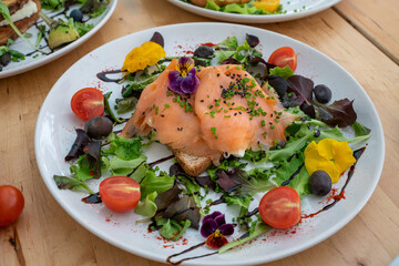 Danish open sandwich Smorrebrod with salmon on rye bread with vegetables and herbs
