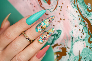 Creative color manicure with rhinestones on long nails.