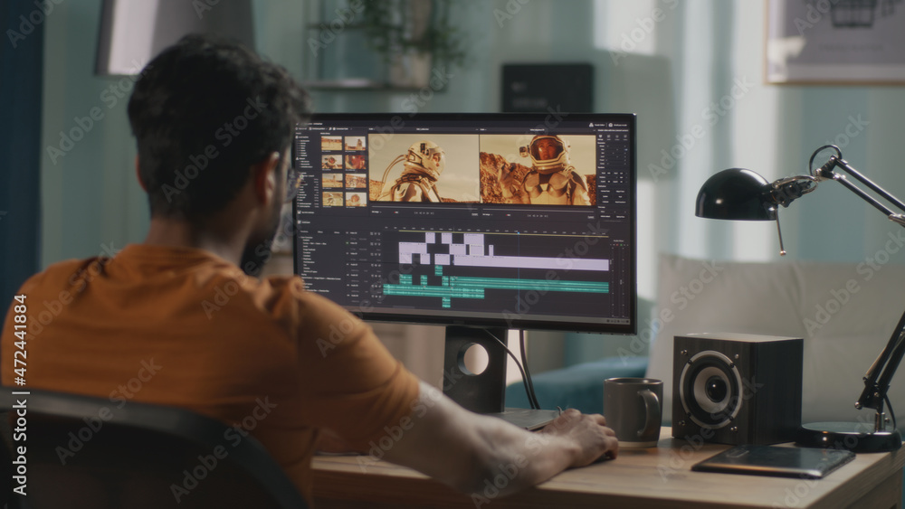 Poster back view of male content creator using computer to edit cosmonaut video during remote work from hom