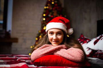 A girl IN SANTA'S HAT against the background of a New Year tree.