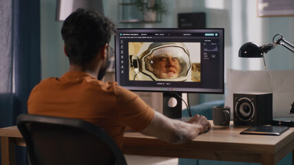 Back view of unrecognizable male retouching astronaut photo on computer while sitting at table and...