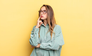 pretty caucasian woman with a concentrated look, wondering with a doubtful expression, looking up...