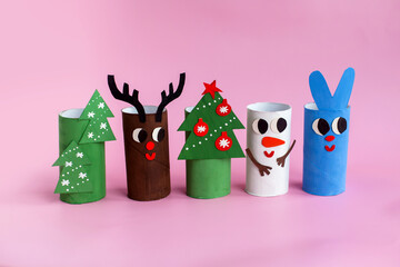 Holiday easy DIY craft idea for kids. Toilet paper roll tube toy Christmas tree, snowman, rabbit, deer on pink background. Creative New Year decoration eco-friendly, reuse, recycle handmade concept
