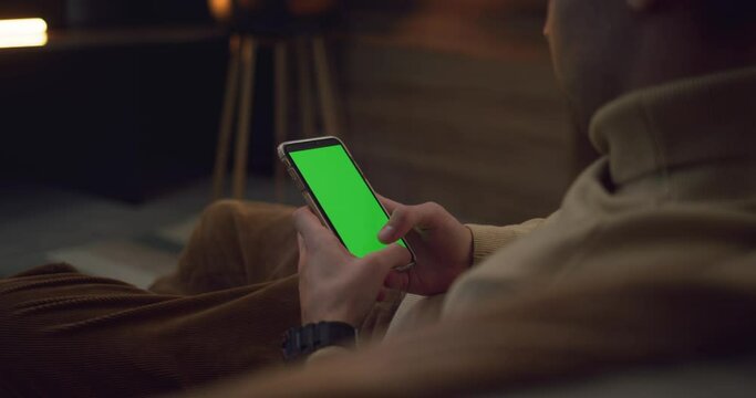 Anonymous person using mobile phone with green screen  for chatting in social media, while having free time at home