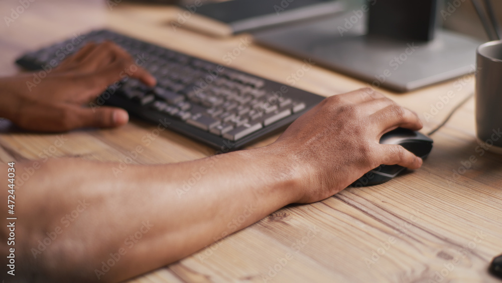 Poster unrecognizable man sitting at table in workplace and using computer mouse and keyboard