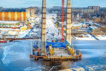 Construction of a new road bridge continues across the Sheksna river. Cable-stayed bridge in Cherepovets. Fragment of the unfinished construction of the city highway.Aerial view.