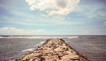 Rocky pier at sea on a sunny summer day, color toning applied, Sri Lanka.