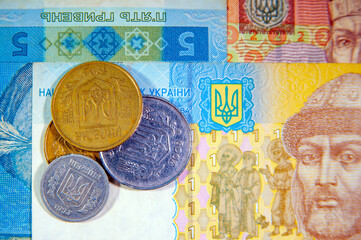 Ukrainian coins in a heap against the background of Ukrainian banknotes in soft focus. Ukrainian money, hryvnia and kopecks, inflation, economic crisis. UAH