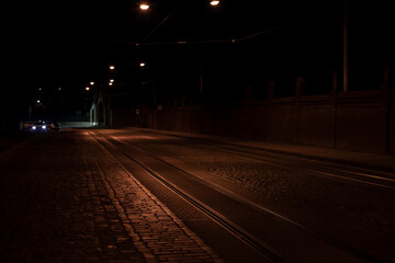 Fototapeta na wymiar night empty street pavement old European road with background car headlight, soft focus concept