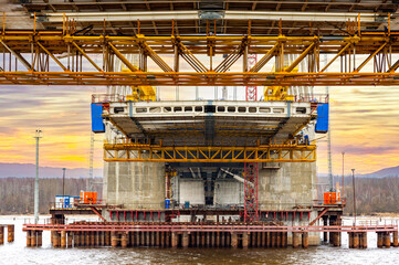 Construction of a new road bridge continues across the Sheksna river. Cable-stayed bridge  at sunset. Fragment of the unfinished construction of the city highway.Repair, stop to drive.