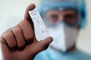 Medical laboratory assistant holding positive COVID-19 rapid test.