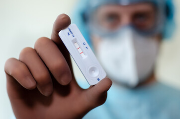 Medical laboratory assistant holding positive COVID-19 rapid test.