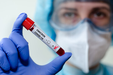 Medical laboratory assistant holding test tube with positive Omicron COVID-19 test blood sample.