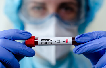 Medical laboratory assistant holding test tube with positive Omicron COVID-19 test blood sample.