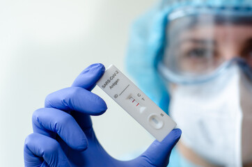 Medical laboratory assistant holding positive COVID-19 rapid test.