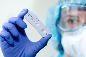 Medical laboratory assistant holding positive COVID-19 rapid test.