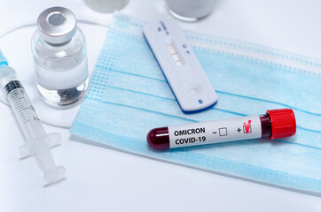 Test tube with positive  Omicron COVID-19 test blood sample and positive covid-19 rapid test in the...
