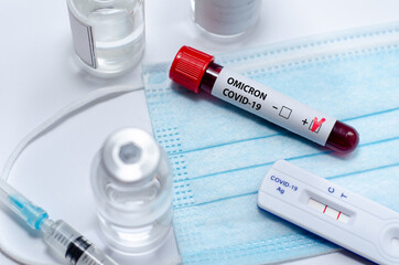 Test tube with positive  Omicron COVID-19 test blood sample and positive covid-19 rapid test in the medical laboratory.