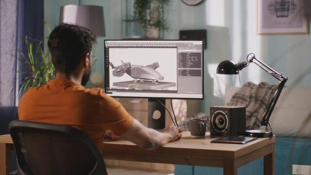 Side view of bearded Indian guy using computer to create 3D model of futuristic aircraft while working remotely from home