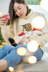 asian woman smile and happy during play and clothing red santa blanket to her cat