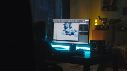 Anonymous teenager in headphones making 3D model of robot on computer while creating cartoon at night at home