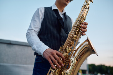 Saxophonist plays melody at the stairs on street