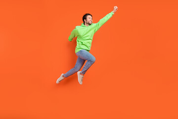 Full length photo of brunet millennial guy run save wear sweater jeans sneakers isolated on orange background