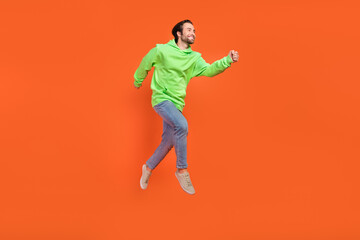 Obraz na płótnie Canvas Full length photo of brunet millennial guy run wear sweatshirt jeans shoes isolated on orange background