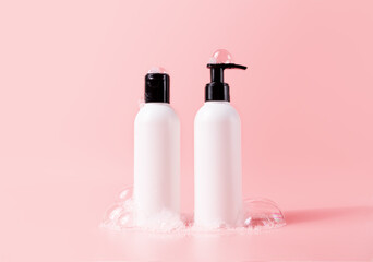 Shampoo and hair conditioner bottle with soapy bubbles. Plastic white packing with black cap beauty...