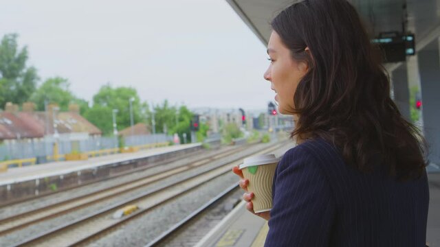 Two businesswomen commuting to work waiting for train on station platform talking together - shot in slow motion