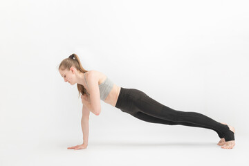 Exercise plank. Young slender woman practices yoga on white background. Fitness trainer. Yoga class.