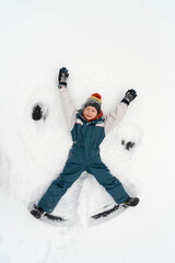Fototapeta na wymiar Snow angel made by kid in the snow. Boy lies in the snow. Winter vacation. Top view.