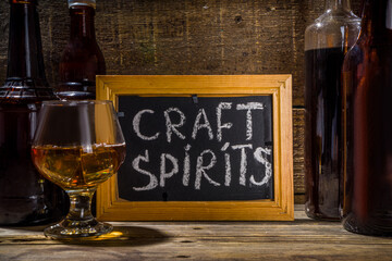 Craft spirit alcohol. Various bottles and glass with hand crafted hard strong alcohol drinks. Old...
