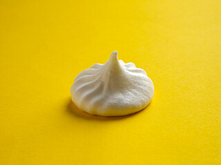 Fototapeta na wymiar Side view of one meringue on a colorful yellow background.