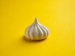 Fototapeta na wymiar Side view of one meringue on a colorful yellow background.
