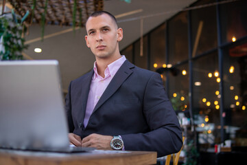 Young handsome businessman working on his laptop while sitting in a cafe