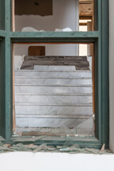 View from the broken window on an old staircase in an abandoned house with an interior destroyed by vandals