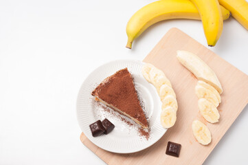 Sweet dessert. A piece of banana cake with marshmallows, pieces of a dark chocolate and banana slices. Top view