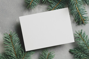Christmas greeting card mockup with fir tree branches on grey background