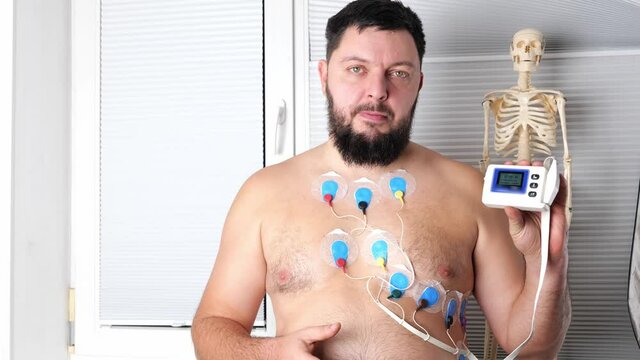 A man wearing portable holter monitor device connected to chest, setting programming. Recording cardiogram for 24 hours. Heart activity, diagnosis, prevention, monitoring and method of heart problems 
